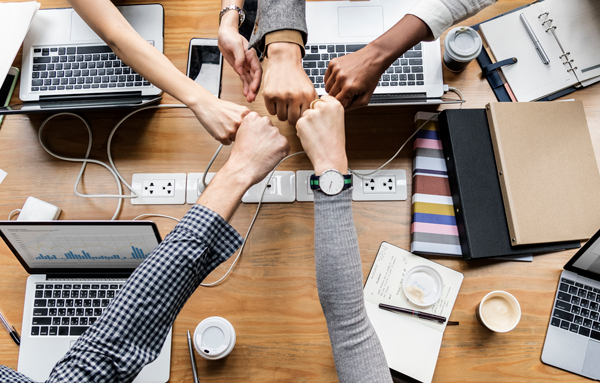 colleagues fist bump around office work table